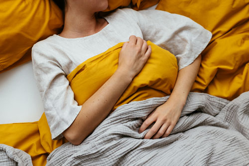 Unrecognizable woman sleeping in bed at home