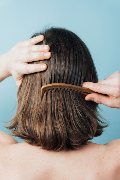 woman combing her hair on blue background