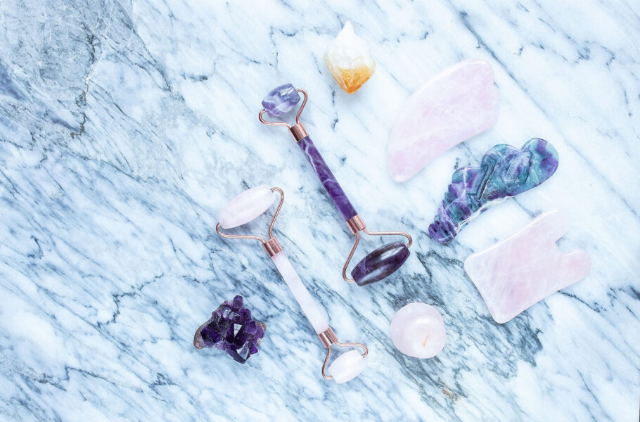still life of jade rollers, guasha facial massage tools on blue marble