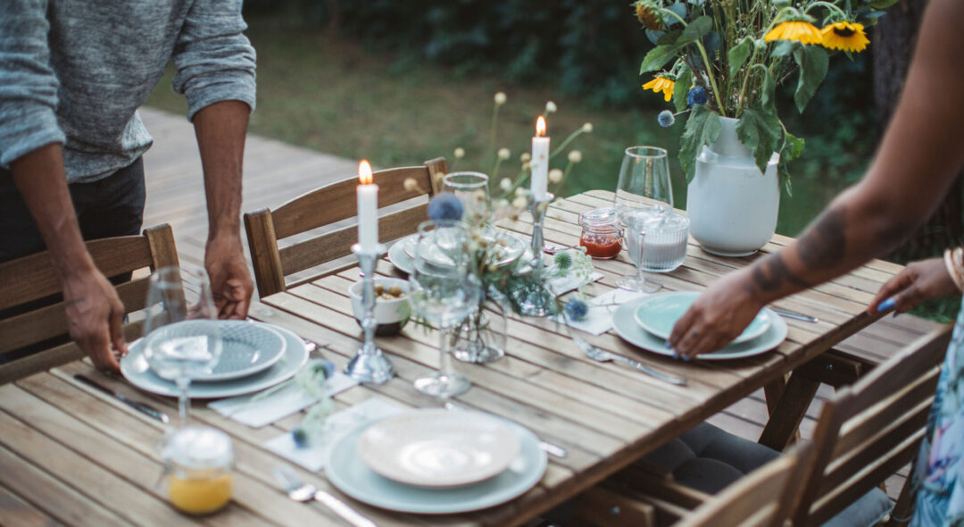 Couple preparing dinner table in backyard of the cottage.