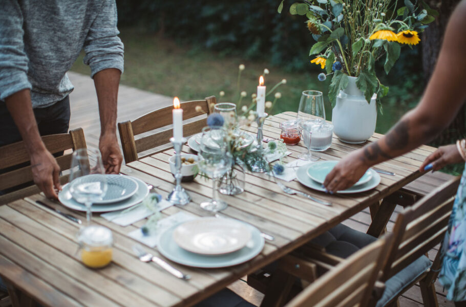 Couple preparing dinner table in backyard of the cottage.