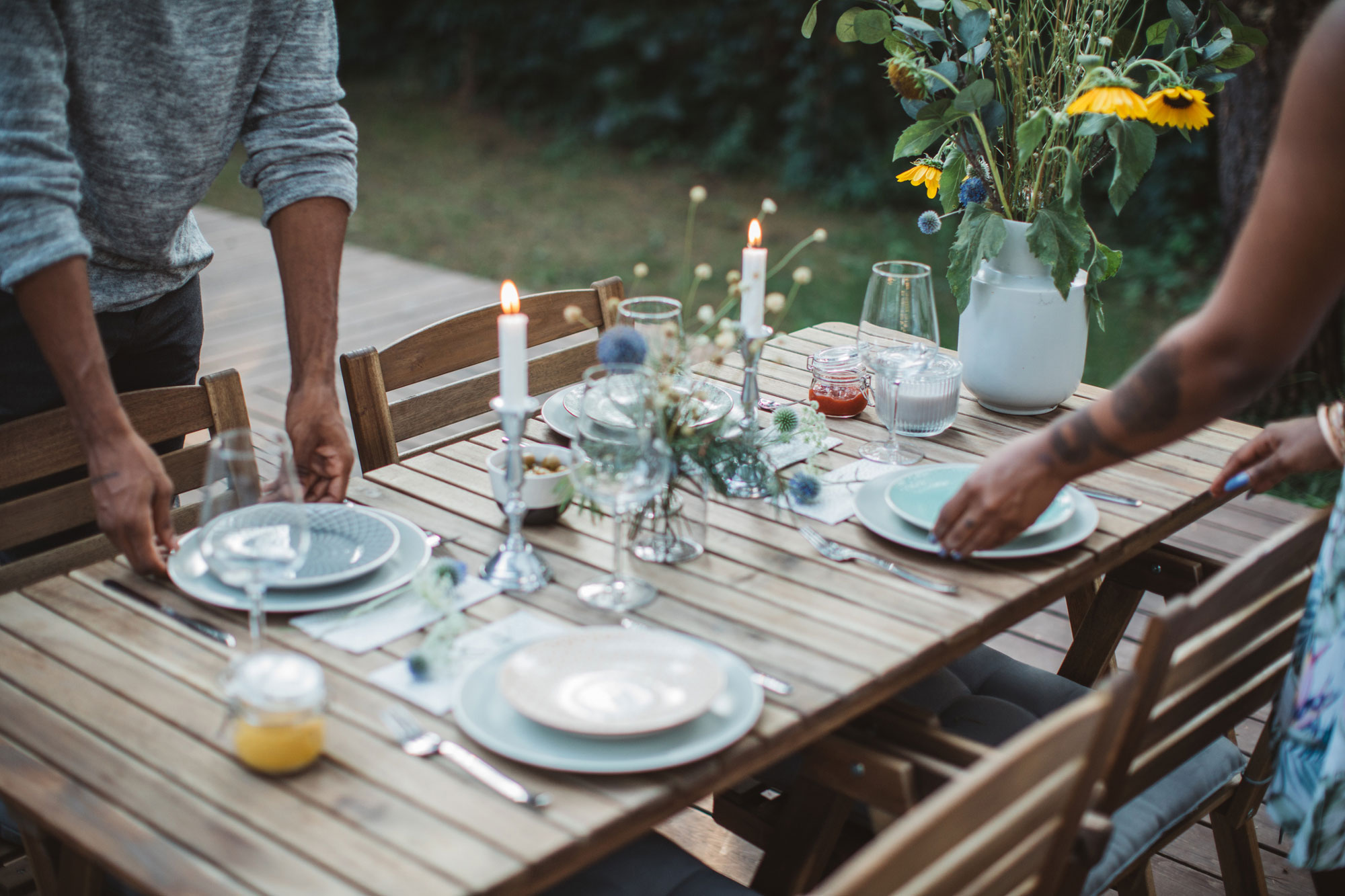 Couple preparing dinner table in backyard of the cottage.