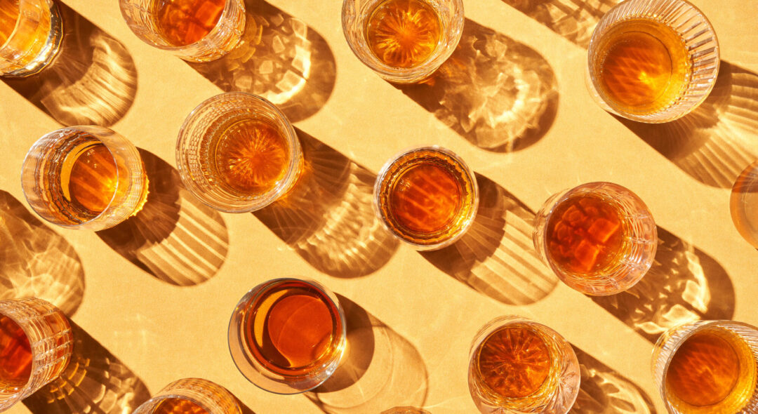 Cups with alcohol beverage on yellow background
