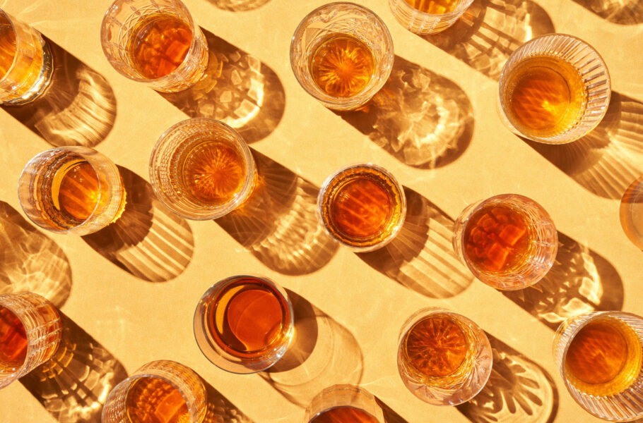 Cups with alcohol beverage on yellow background