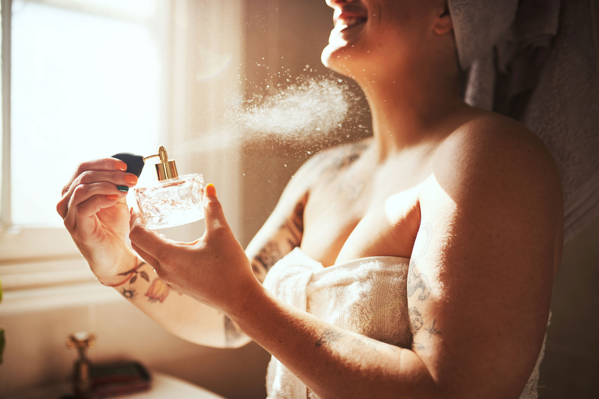woman spraying perfume after showering