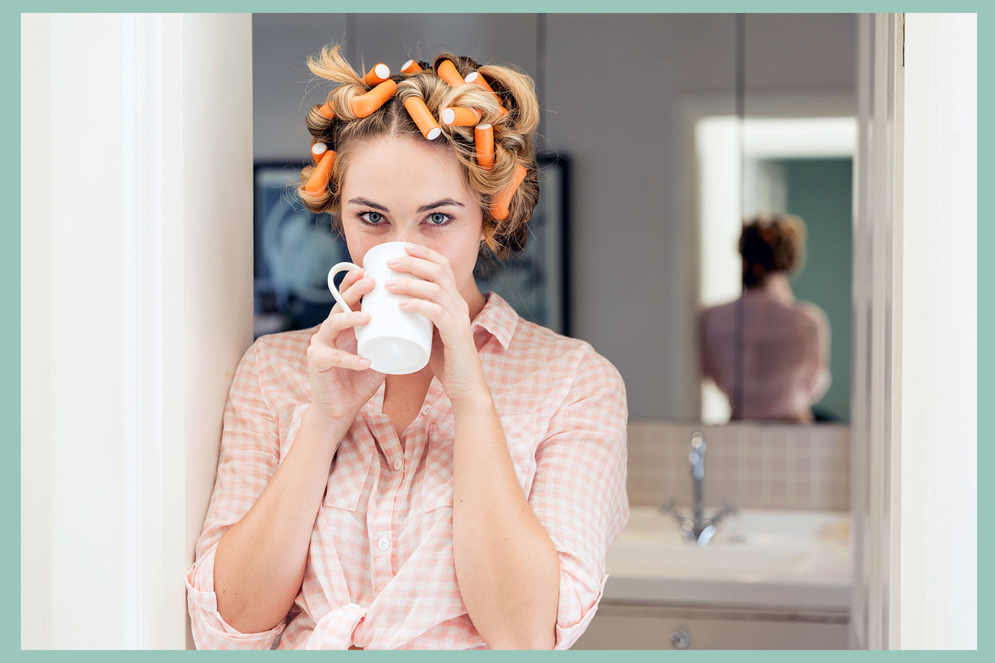 Portrait of young woman with curlers in hair drinking coffee