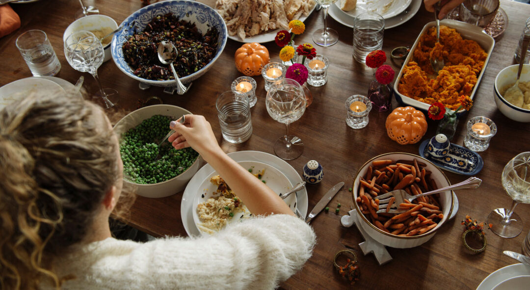 woman having food while sitting at dining table during Thanksgiving