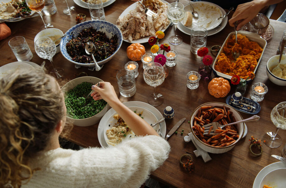 woman having food while sitting at dining table during Thanksgiving