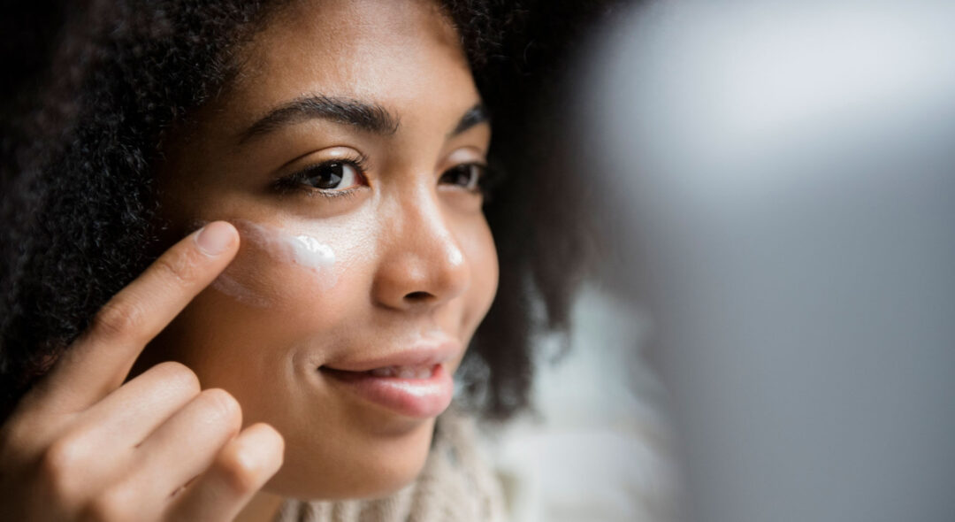 Close up of woman applying lotion to face