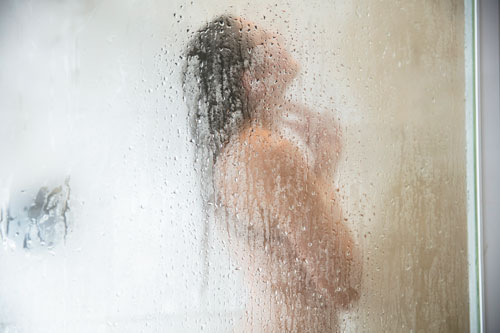 woman in shower behind steamed glass door