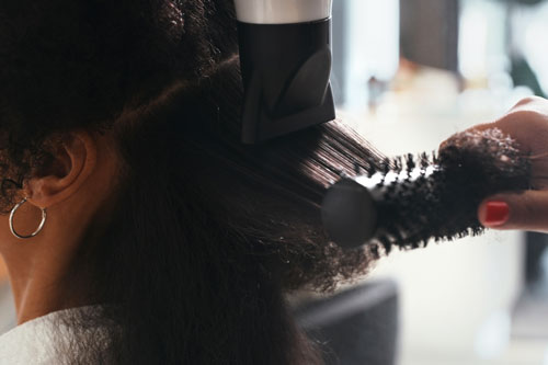 Shot of a stylist blowdrying a client's hair at a salon