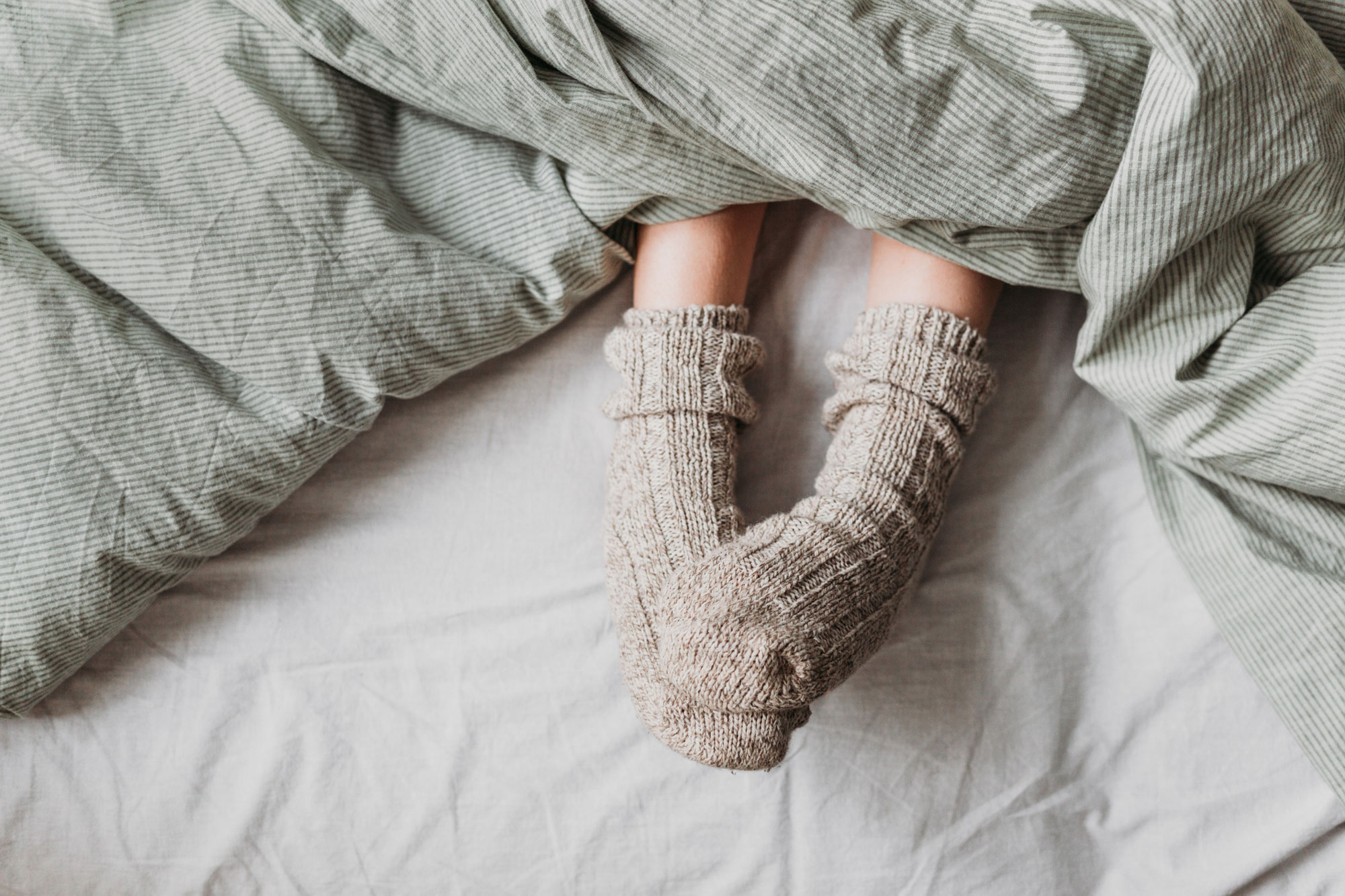 close up of person wearing socks under covers