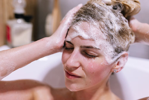woman applying shampoo on hair