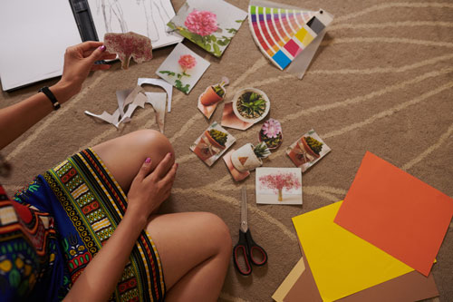 woman sitting on floor and cutting out varioius pictures for collage