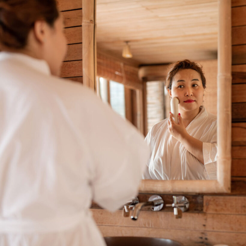 woman using facial device in mirror