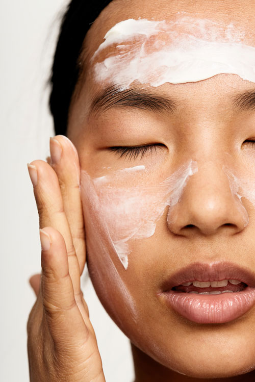 Woman Applying lotion Over Face Skincare Treatment