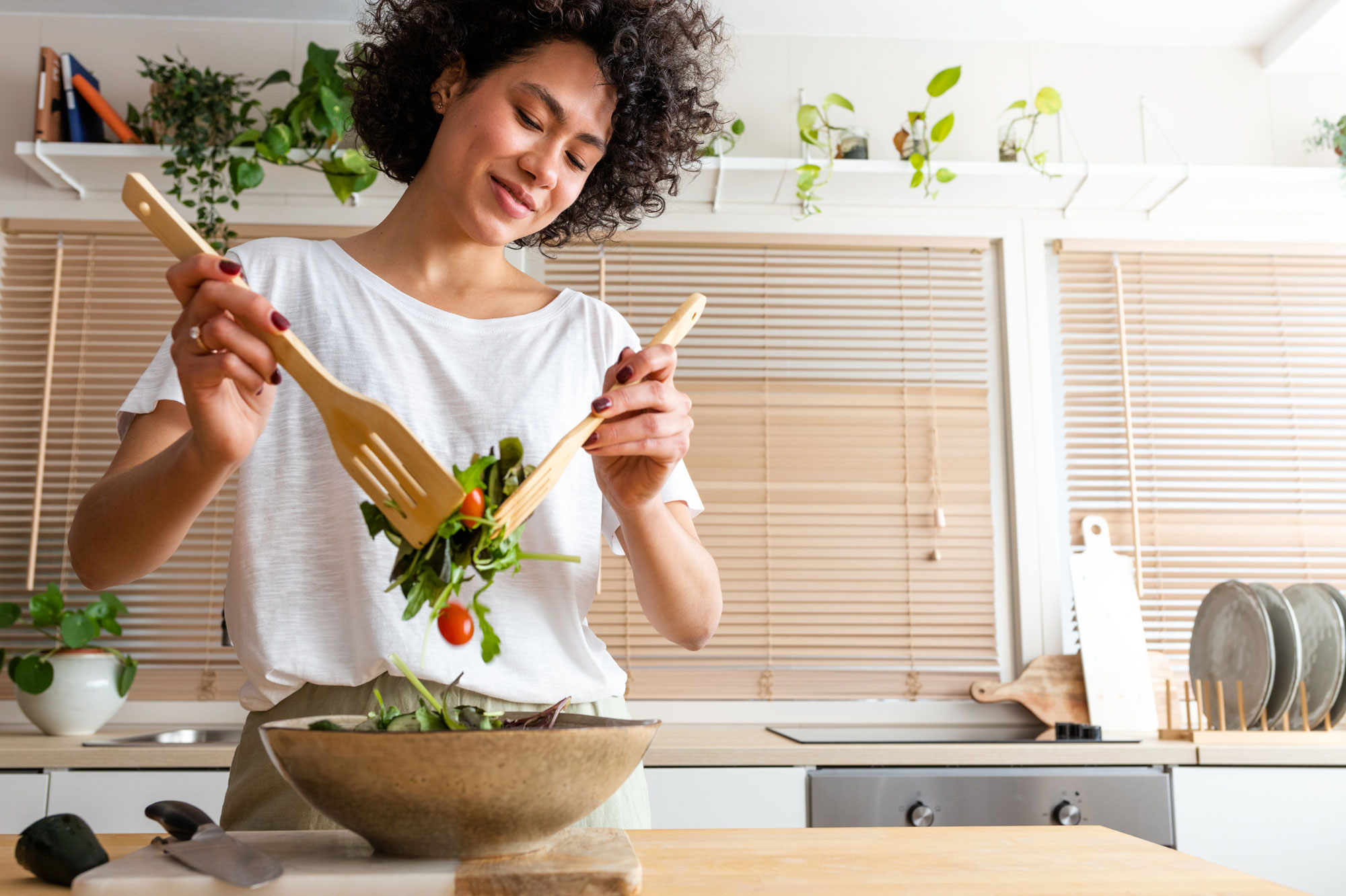 woman mixing bowl of fresh salad in kitchen