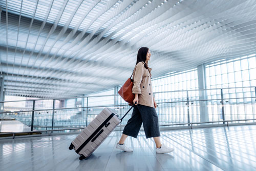 woman carrying suitcase walking in airport terminal