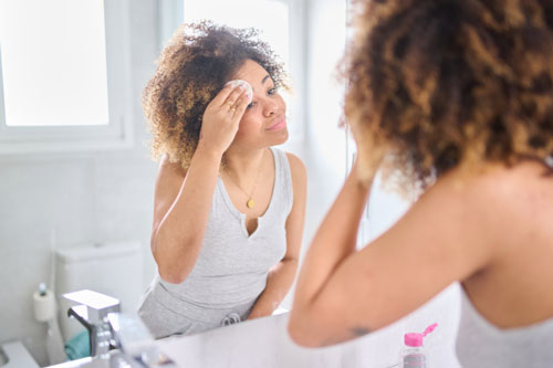Woman removing make-up in mirror in bathroom