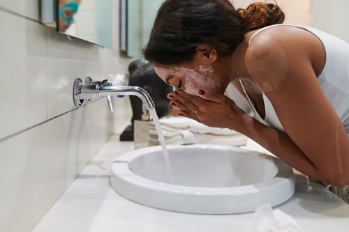 Woman washing off a face mask