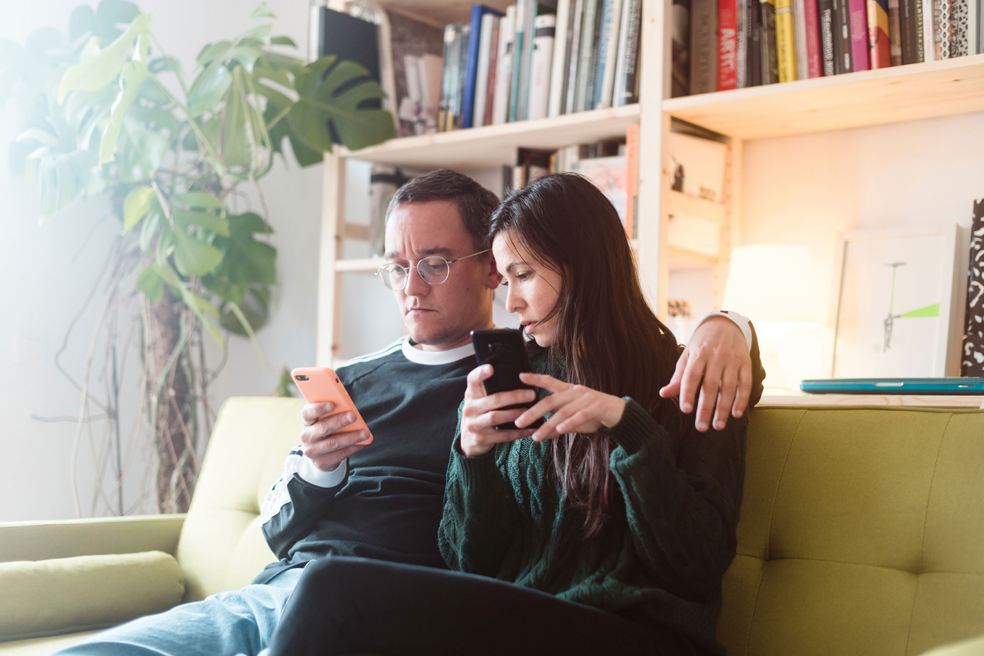 Couple sitting together in couch looking at phone