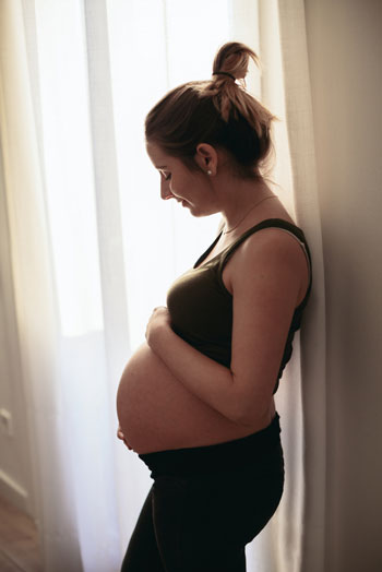 Pregnant woman near a window at home