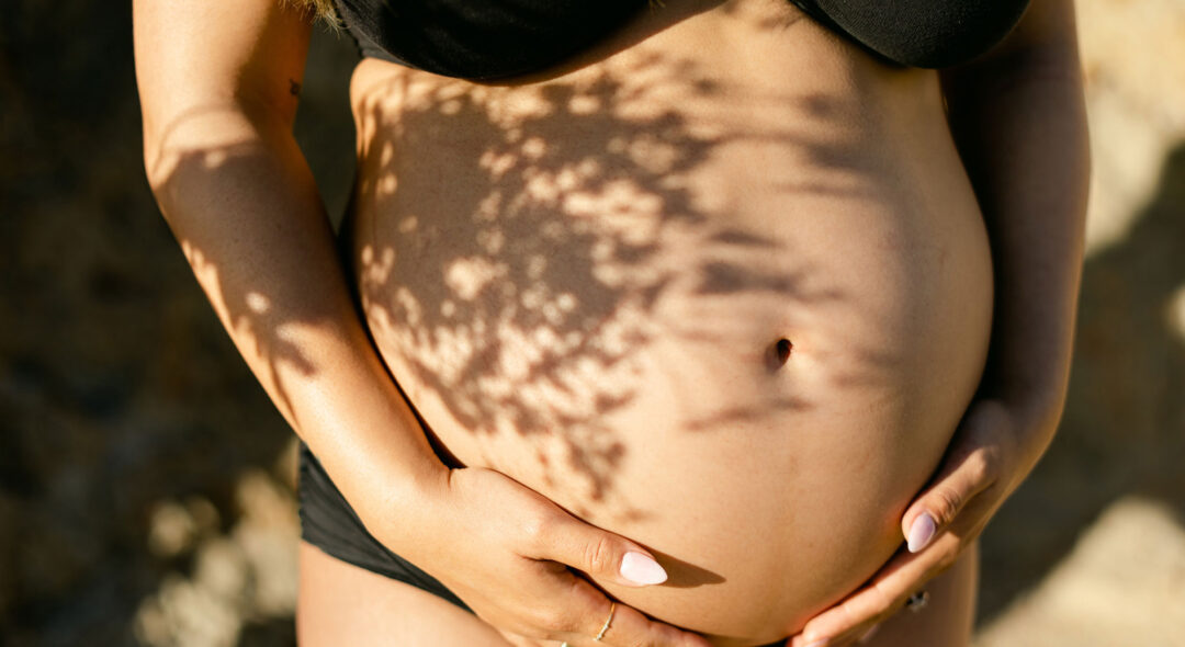 Closeup of Pregnant Woman Holding Belly with Botanical Shadows
