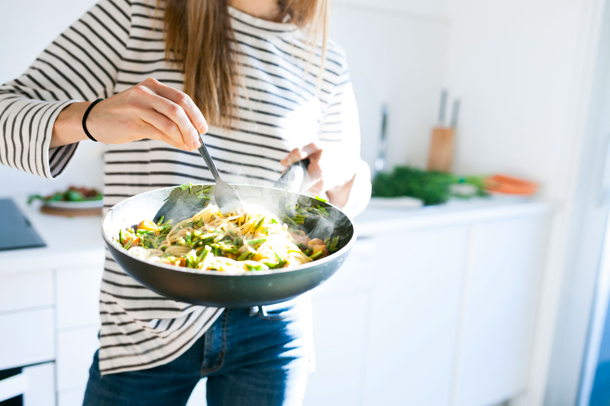 woman holding pan with vegan pasta dish