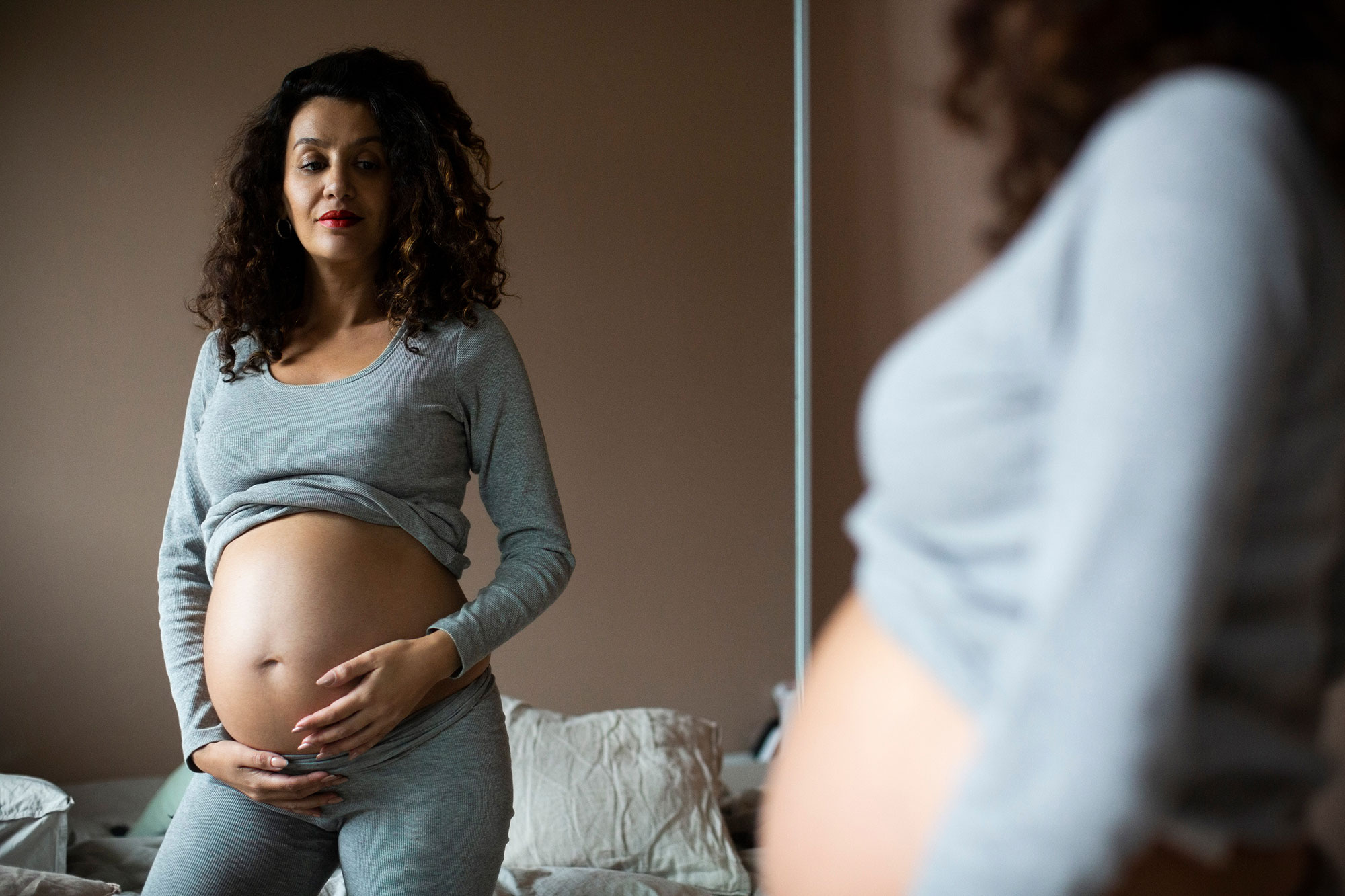 pregnant woman looking at mirror