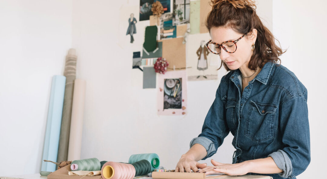 Woman Choosing Color Sample For Moodboard On Wooden Table