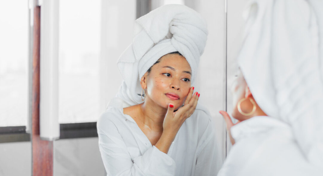 woman applying skincare in mirror
