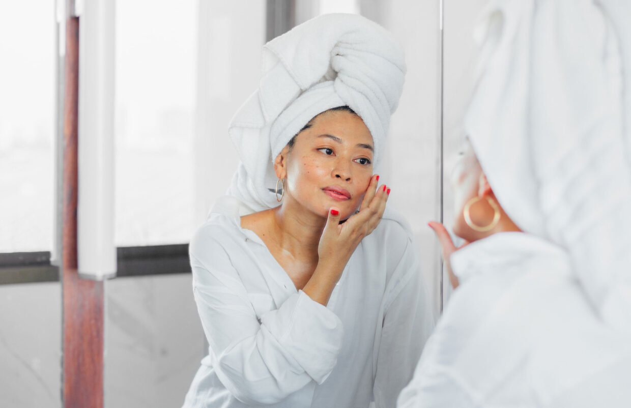 woman applying skincare in mirror