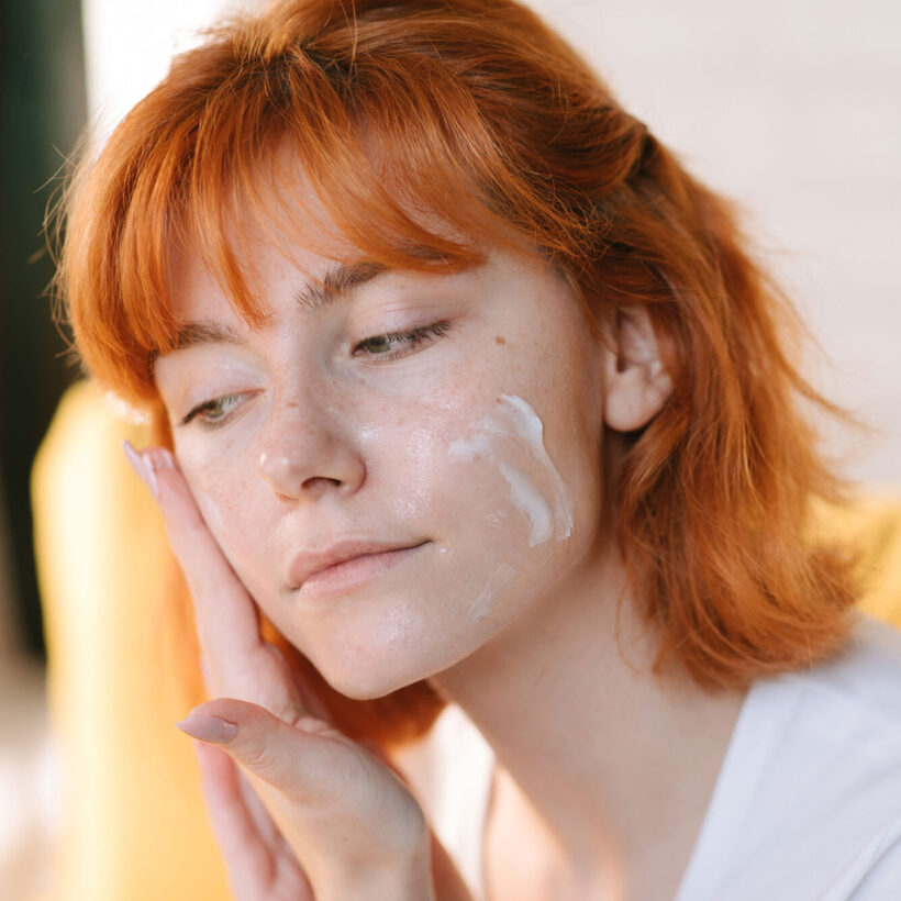 woman applying moisturizer on face