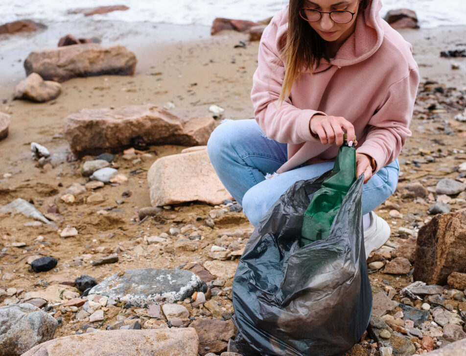 woman collecting litter near sea