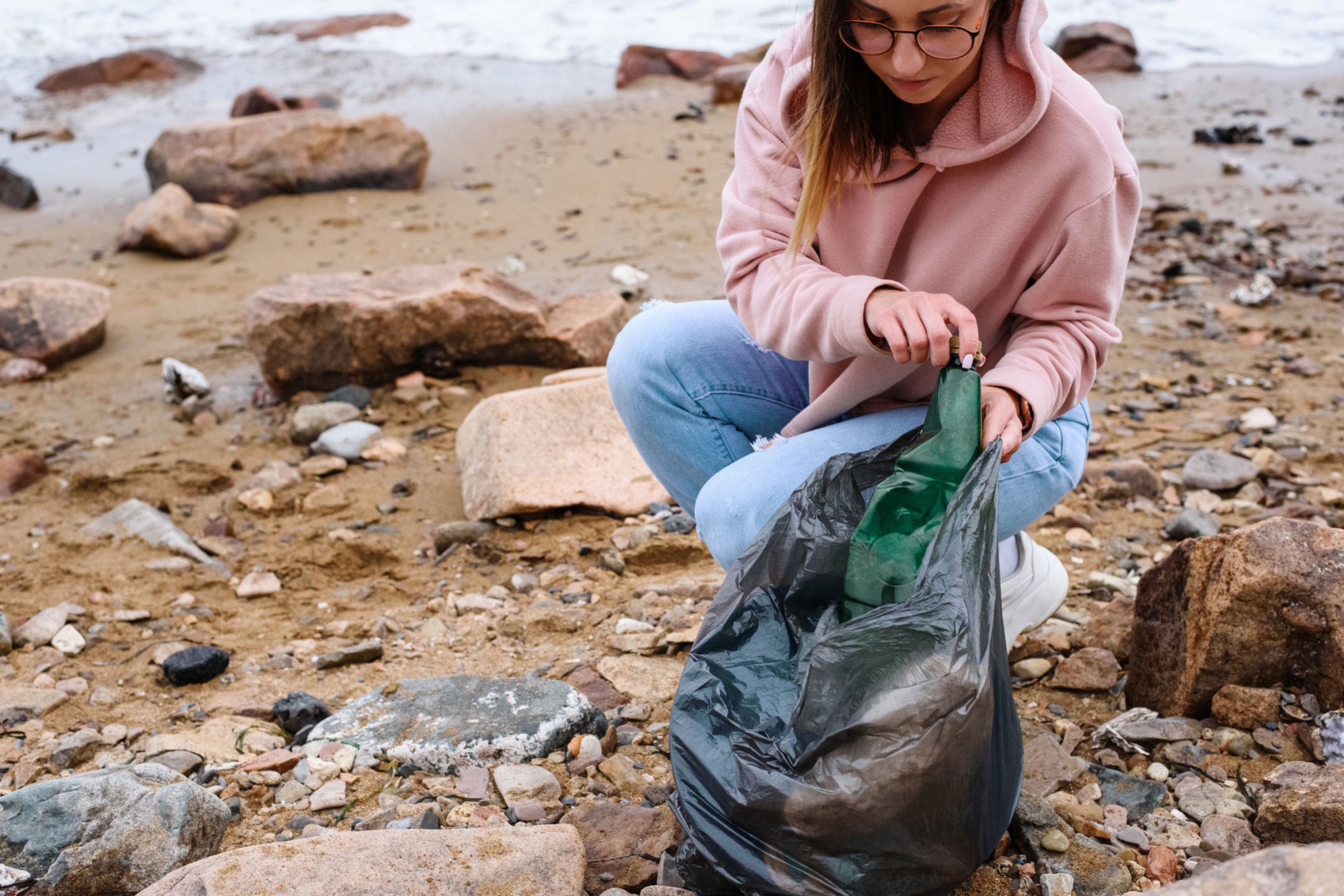woman collecting litter near sea