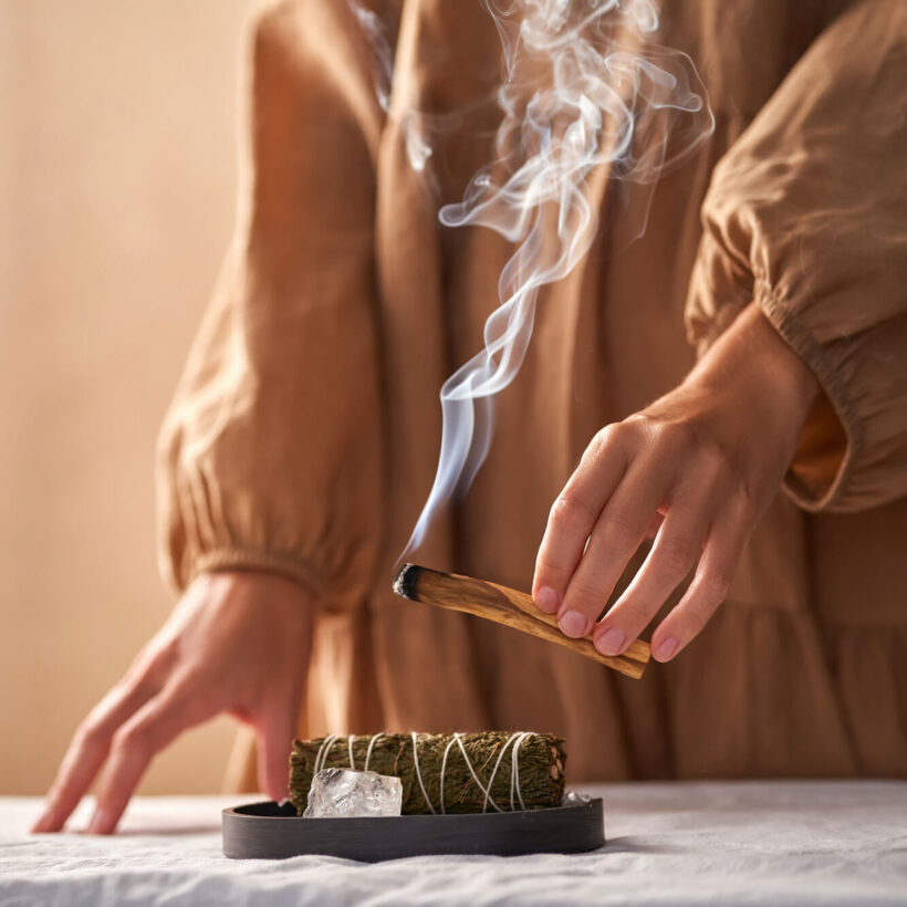 close up of woman holding palo santo stick burning