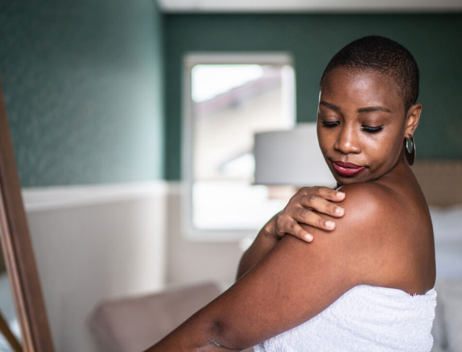 Woman wearing a towel applying moisturizer