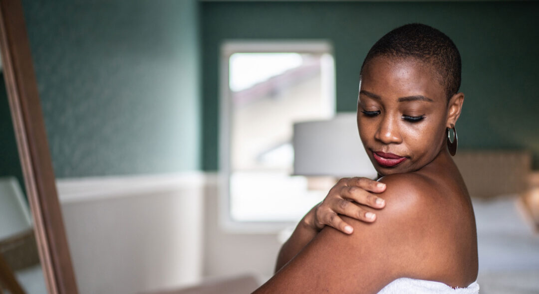 Woman wearing a towel applying moisturizer